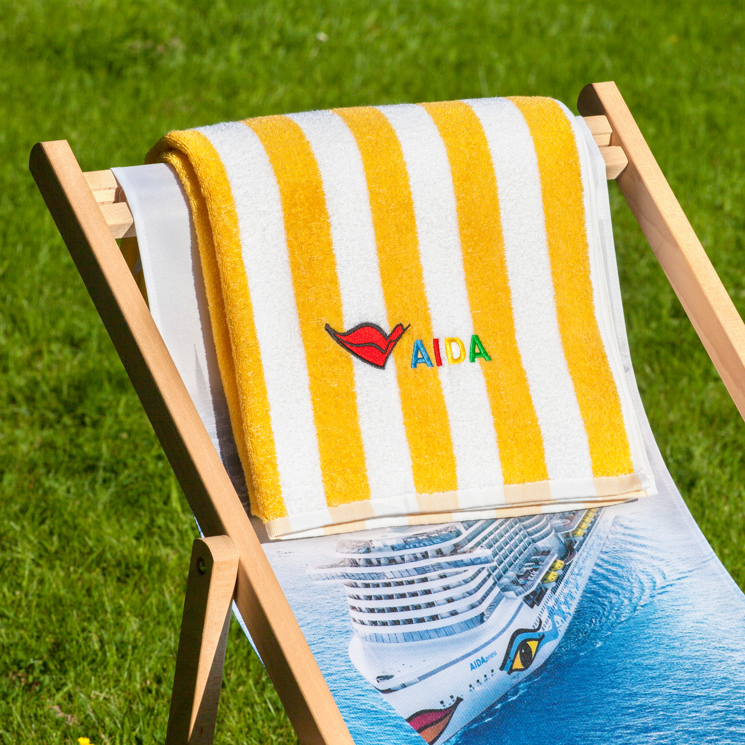 Gelb-weiß gestreiftes Frotteehandtuch mit gesticktem AIDA-Logo, rechteckig gefaltet – AIDA Pool-Handtuch (70 × 200 cm).